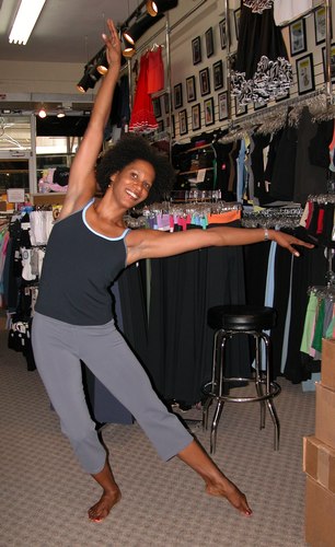 Black top with cornflower blue and grey trim. Grey pants. Clothing by AMMA. Modeled by Kendra Jackson. Available at <a href='http://www.onstagedancewear.com'>OnStageDancewear.com</a>.